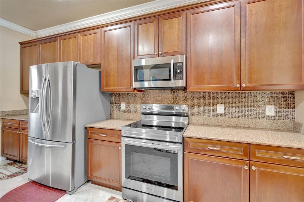 6932 Gray Catbird Loop Wesley Chapel, FL 33545 - Photo 7 of 25 a kitchen with stainless steel appliances granite countertop a refrigerator sink and cabinets