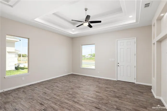 a view of an empty room with a window and wooden floor