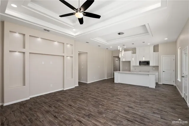 a view of an empty room with wooden floor and a ceiling fan