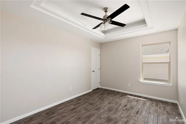an empty room with wooden floor ceiling fan and windows