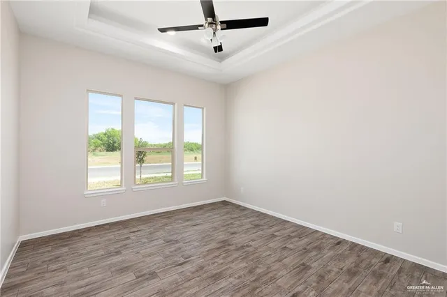 an empty room with wooden floor ceiling fan and windows