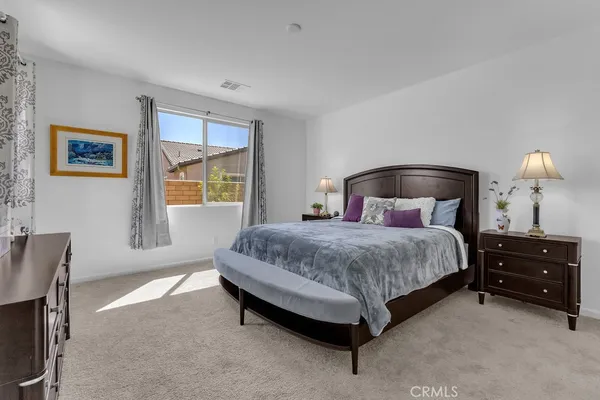 a bedroom with a bed and a lamp on dresser