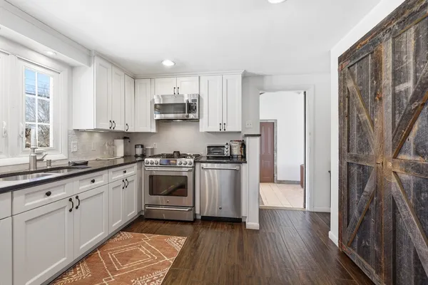 a kitchen with stainless steel appliances granite countertop a refrigerator a stove top oven a sink and dishwasher with wooden floor