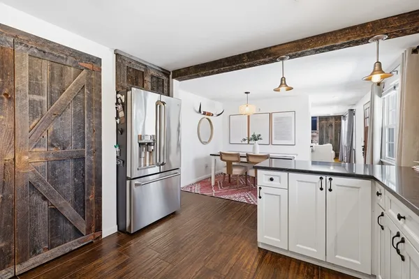 a kitchen with granite countertop a refrigerator a sink and white cabinets