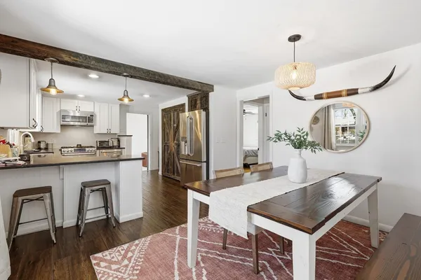 a kitchen with stainless steel appliances granite countertop a stove a refrigerator a kitchen island a dining table and chairs with wooden floor