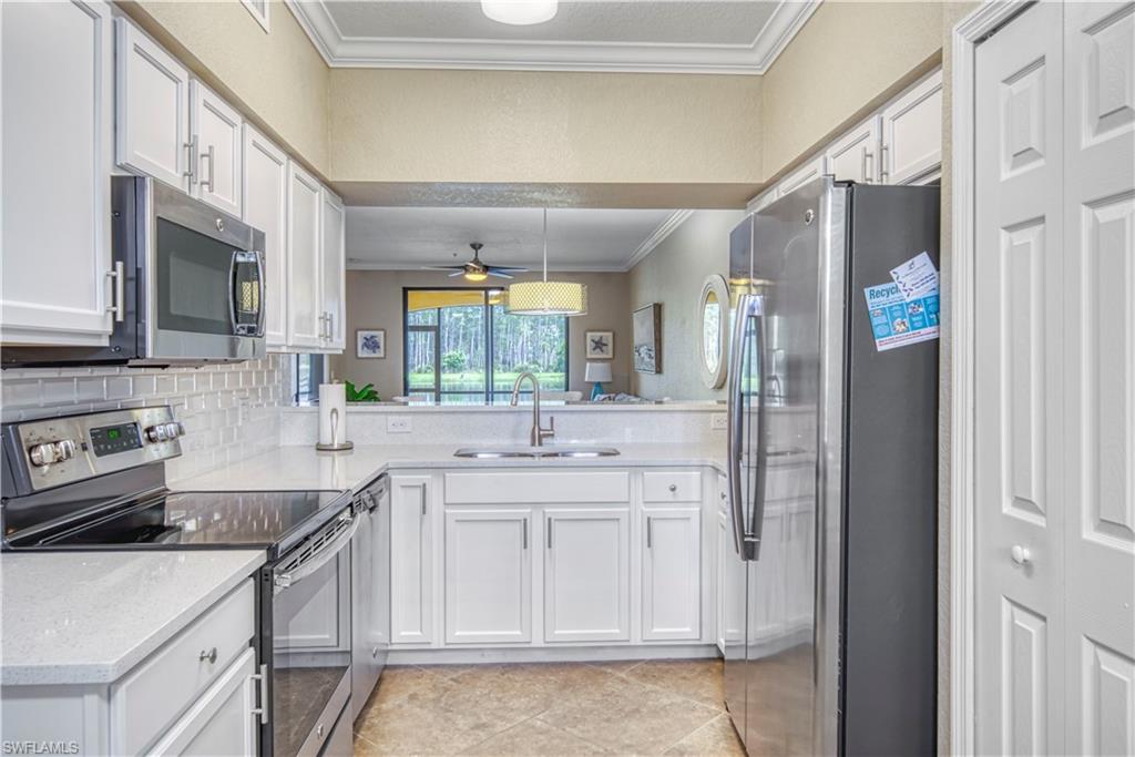 9560 Trevi Court, Unit 4815 Naples, FL 34113 - Photo 11 of 38 a kitchen with stainless steel appliances a sink stove and cabinets