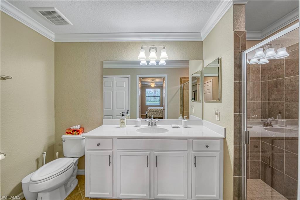 9560 Trevi Court, Unit 4815 Naples, FL 34113 - Photo 19 of 38 a bathroom with a granite countertop sink a toilet and a shower