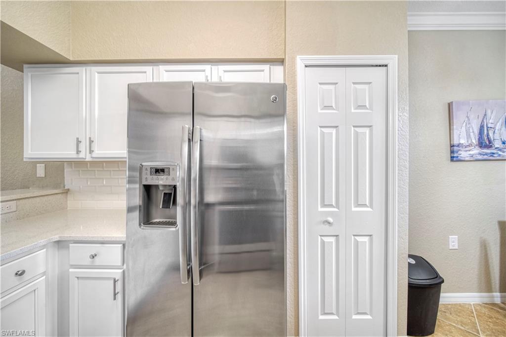 9560 Trevi Court, Unit 4815 Naples, FL 34113 - Photo 8 of 38 a kitchen with a refrigerator and cabinets