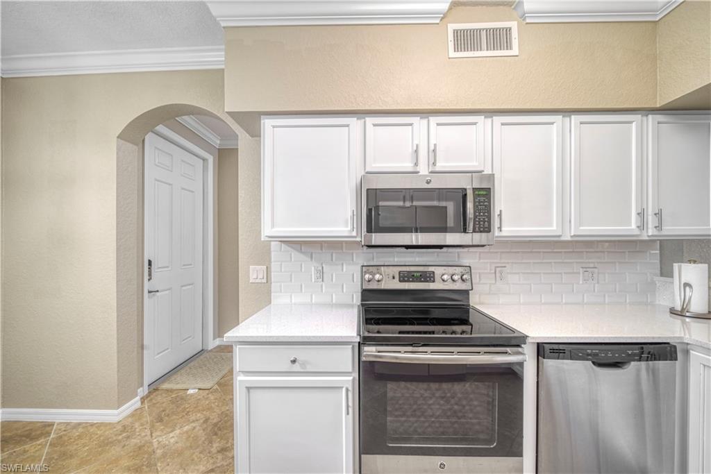 9560 Trevi Court, Unit 4815 Naples, FL 34113 - Photo 9 of 38 a kitchen with stainless steel appliances granite countertop a stove and a microwave