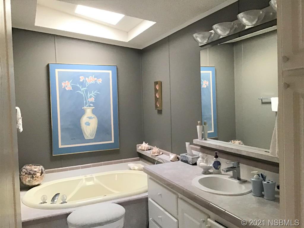 765 Navigators Way Edgewater, FL 32141 - Photo 14 of 34 a bathroom with a granite countertop sink mirror vanity and bathtub