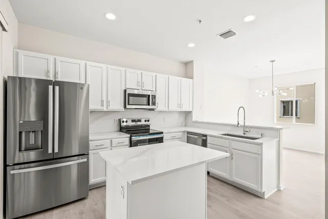 a kitchen with stainless steel appliances a refrigerator sink and microwave
