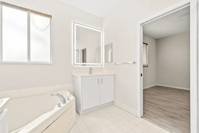 a bathroom with a tub a sink and a mirror