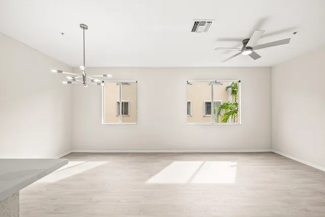 an empty room with windows and ceiling fan