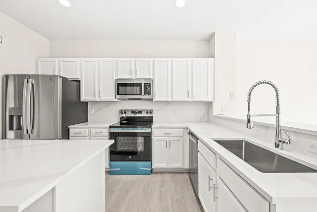 a kitchen with a sink white cabinets and stainless steel appliances