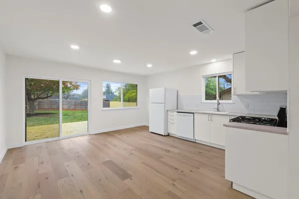 a open kitchen with white cabinets and wooden floor