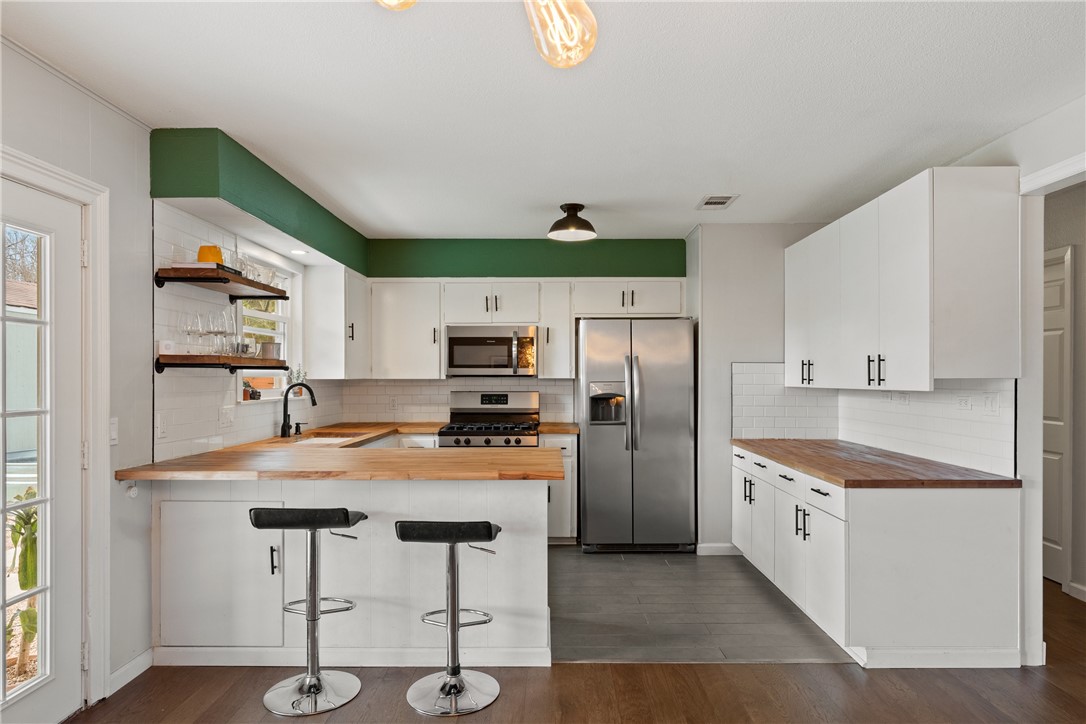 3305 Catalina Drive Austin, TX 78741 - Photo 1 of 1 a kitchen with stainless steel appliances a refrigerator a stove a sink dishwasher and white cabinets with wooden floor