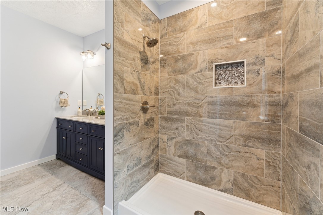 7605 Lake Road East Madison, OH 44057 - Photo 23 of 50 Full bathroom featuring vanity, a tile shower, baseboards, and marble finish floors