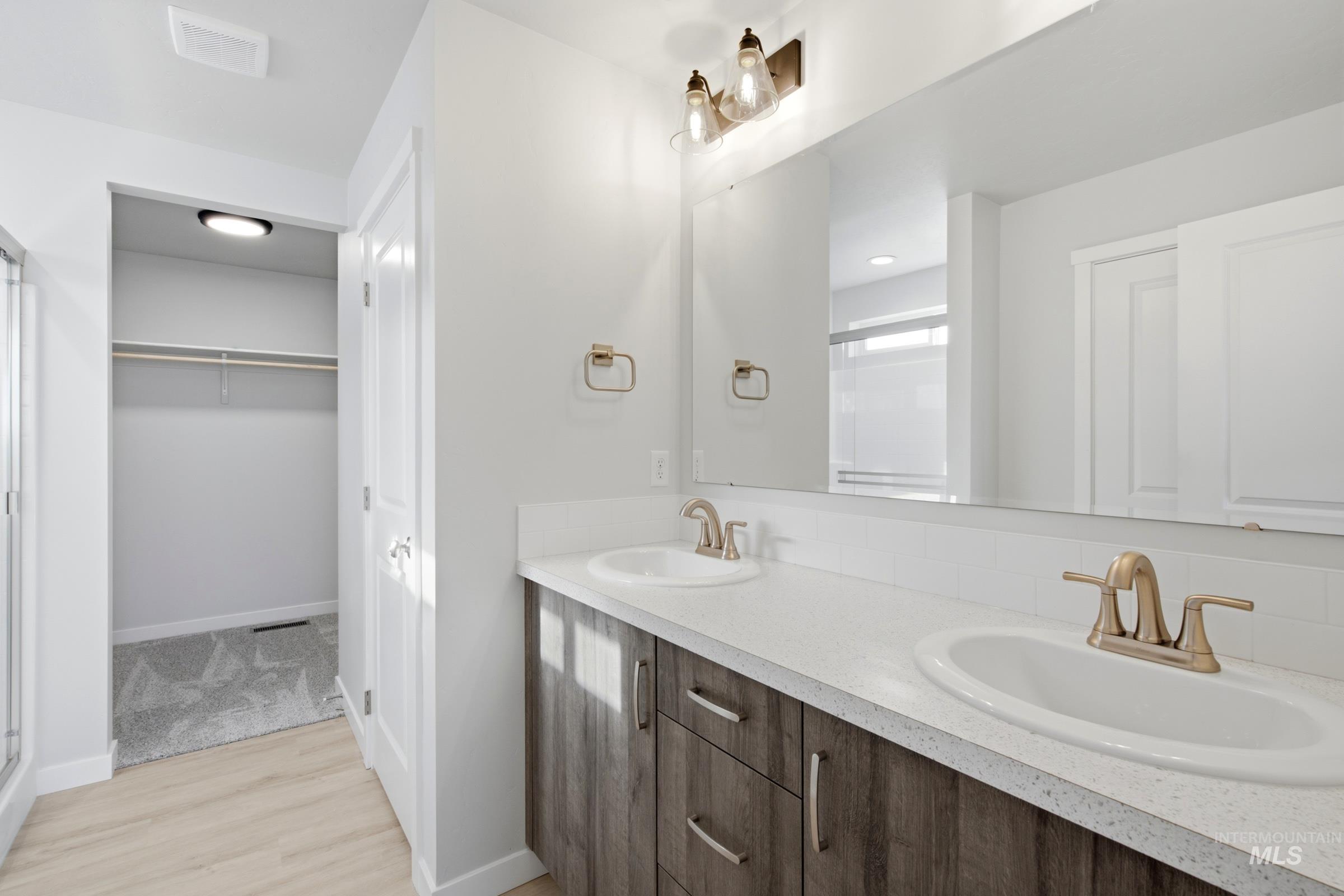 13324 Bank Street Caldwell, ID 83607 - Photo 27 of 29 Dual vanity with gold-tone fixtures, wood-finish cabinetry, and a full-width mirror