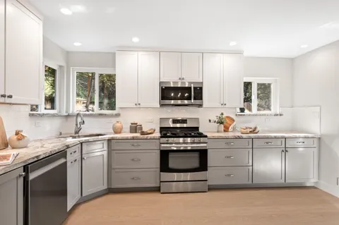 a kitchen with cabinets appliances a sink and a window