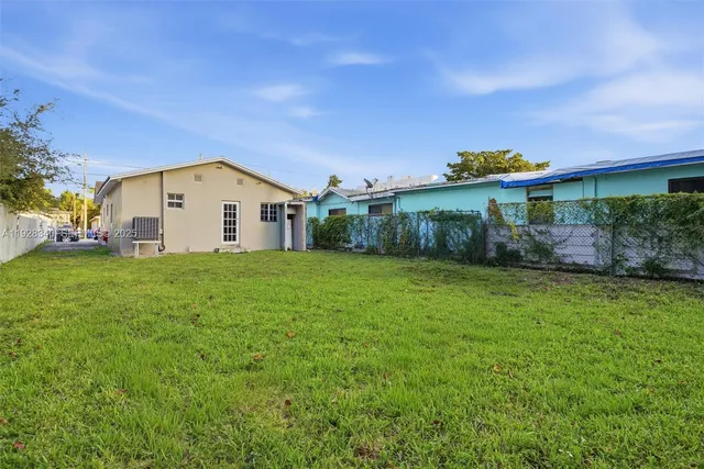 a view of a white house next to a yard with big trees