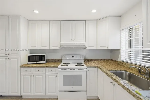 a kitchen with granite countertop white cabinets and white appliances