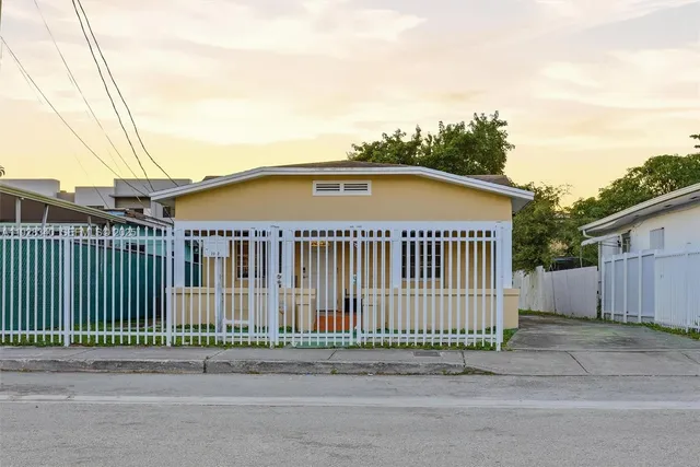 a view of a house with a small yard and wooden fence