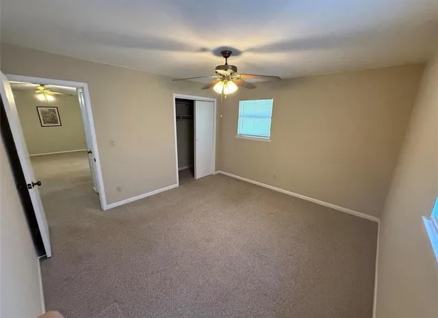 an empty room with a chandelier fan and wooden floor