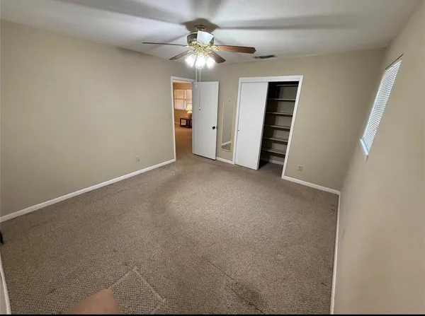 an empty room with closet and a ceiling fan
