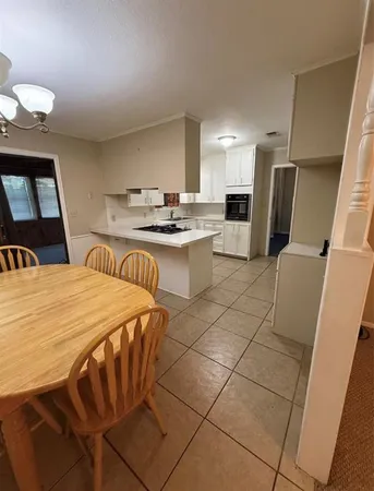 a large kitchen with sink a refrigerator and chairs