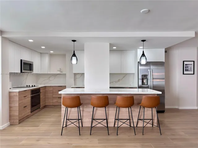a kitchen with stainless steel appliances granite countertop a table chairs sink and stove