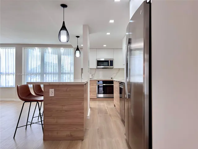 a kitchen with stainless steel appliances granite countertop a stove top oven a sink with a dining table and chairs