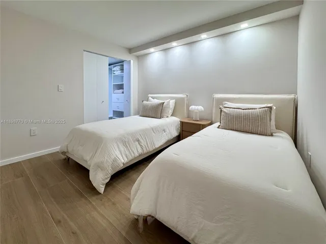 a bedroom with two beds and wooden floor