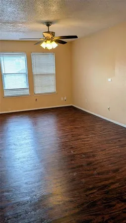 an empty room with wooden floor chandelier fan and windows