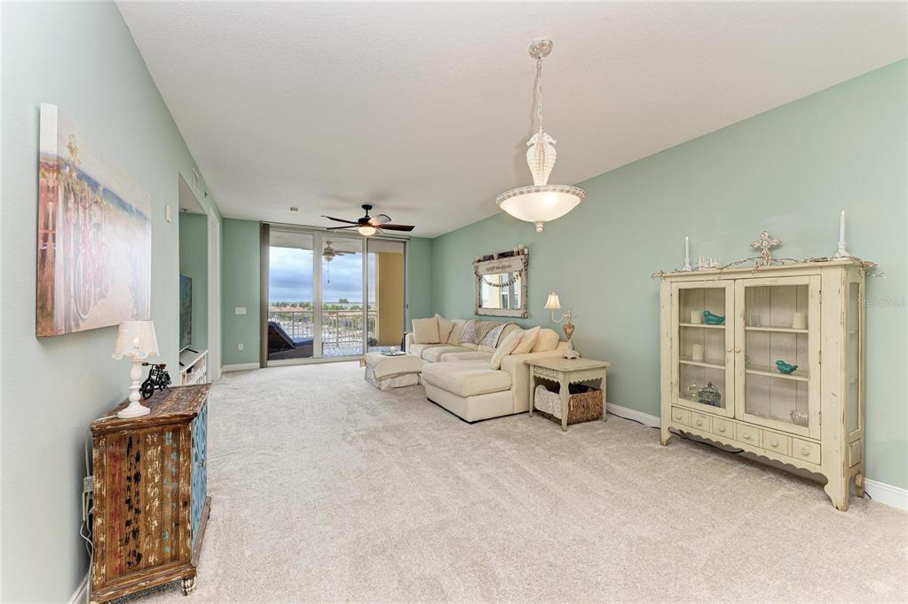 610 Riviera Dunes Way, Unit 406 Palmetto, FL 34221 - Photo 14 of 49 a living room with furniture and a chandelier
