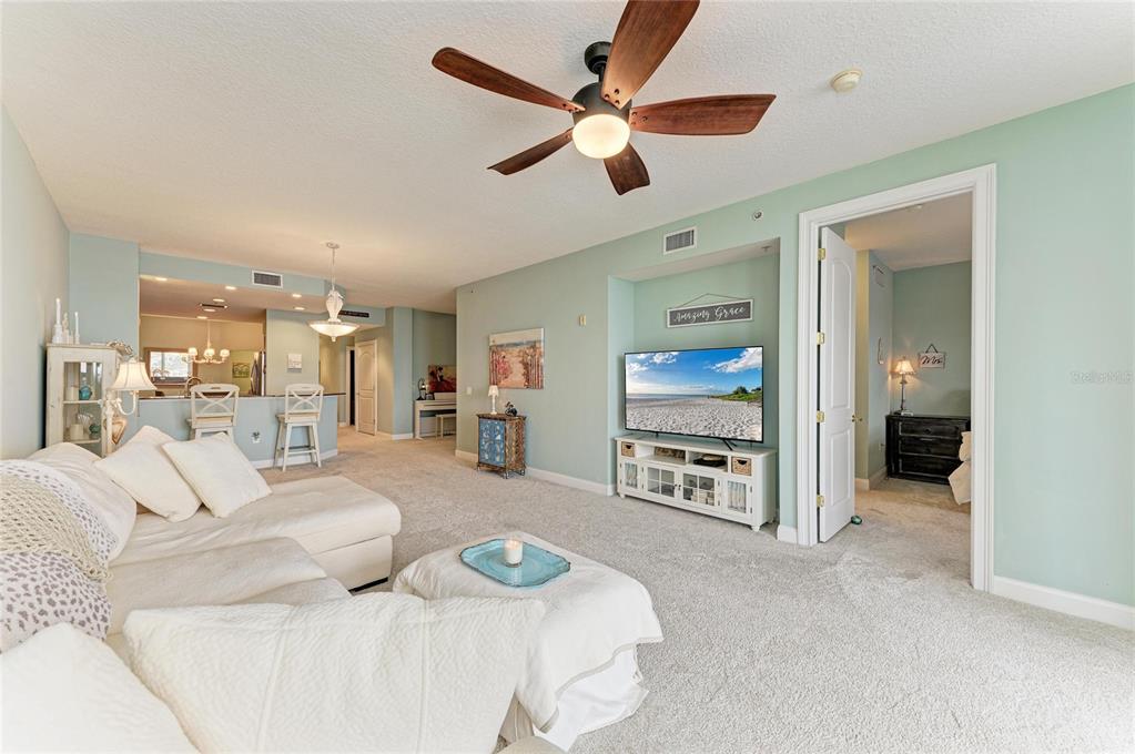 610 Riviera Dunes Way, Unit 406 Palmetto, FL 34221 - Photo 19 of 49 a living room with furniture a ceiling fan and a flat screen tv