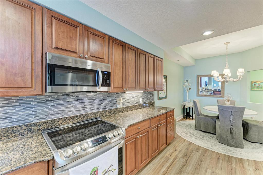 610 Riviera Dunes Way, Unit 406 Palmetto, FL 34221 - Photo 22 of 49 a kitchen with granite countertop a stove top oven microwave and cabinets