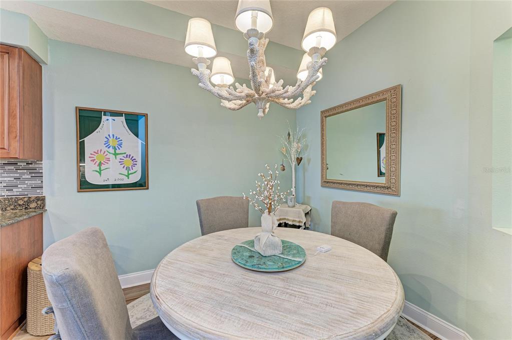 610 Riviera Dunes Way, Unit 406 Palmetto, FL 34221 - Photo 26 of 49 a dining room with wooden floor a chandelier a wooden table and chairs