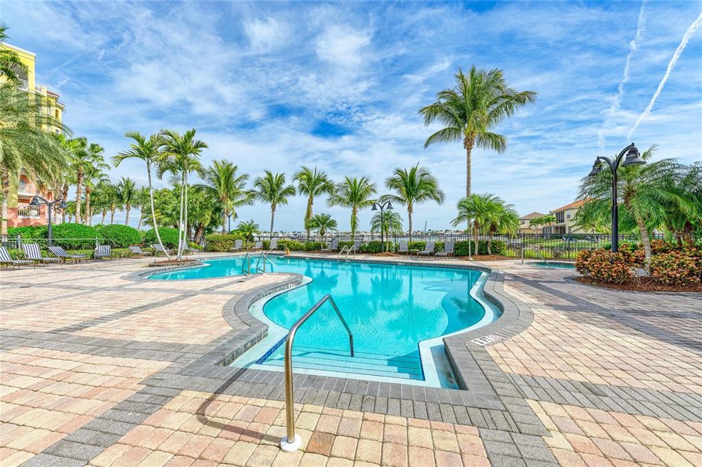 610 Riviera Dunes Way, Unit 406 Palmetto, FL 34221 - Photo 39 of 49 a view of a swimming pool with a lounge chair and palm trees