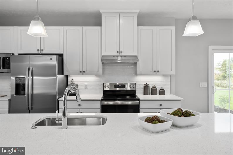 3422 Fox Pointe Lane York, PA 17404 - Photo 14 of 27 a kitchen with kitchen island a stove a sink and a refrigerator with white cabinets