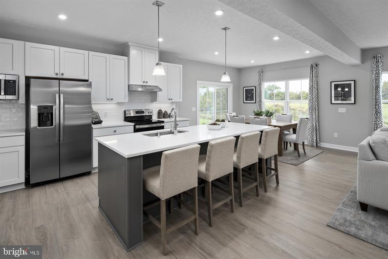 3422 Fox Pointe Lane York, PA 17404 - Photo 15 of 27 a kitchen with stainless steel appliances granite countertop a stove a refrigerator a kitchen island a dining table and chairs with wooden floor
