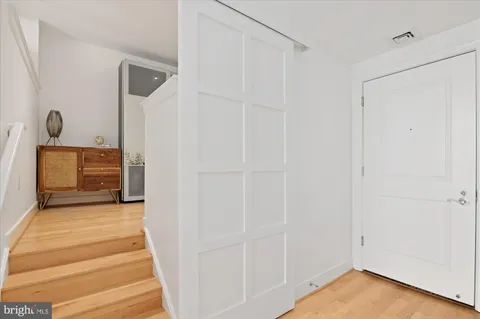 a view of front door with hallway and wooden floor