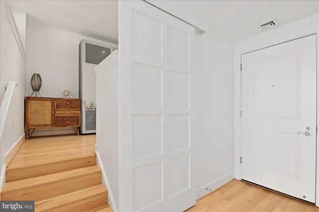 a view of front door with hallway and wooden floor