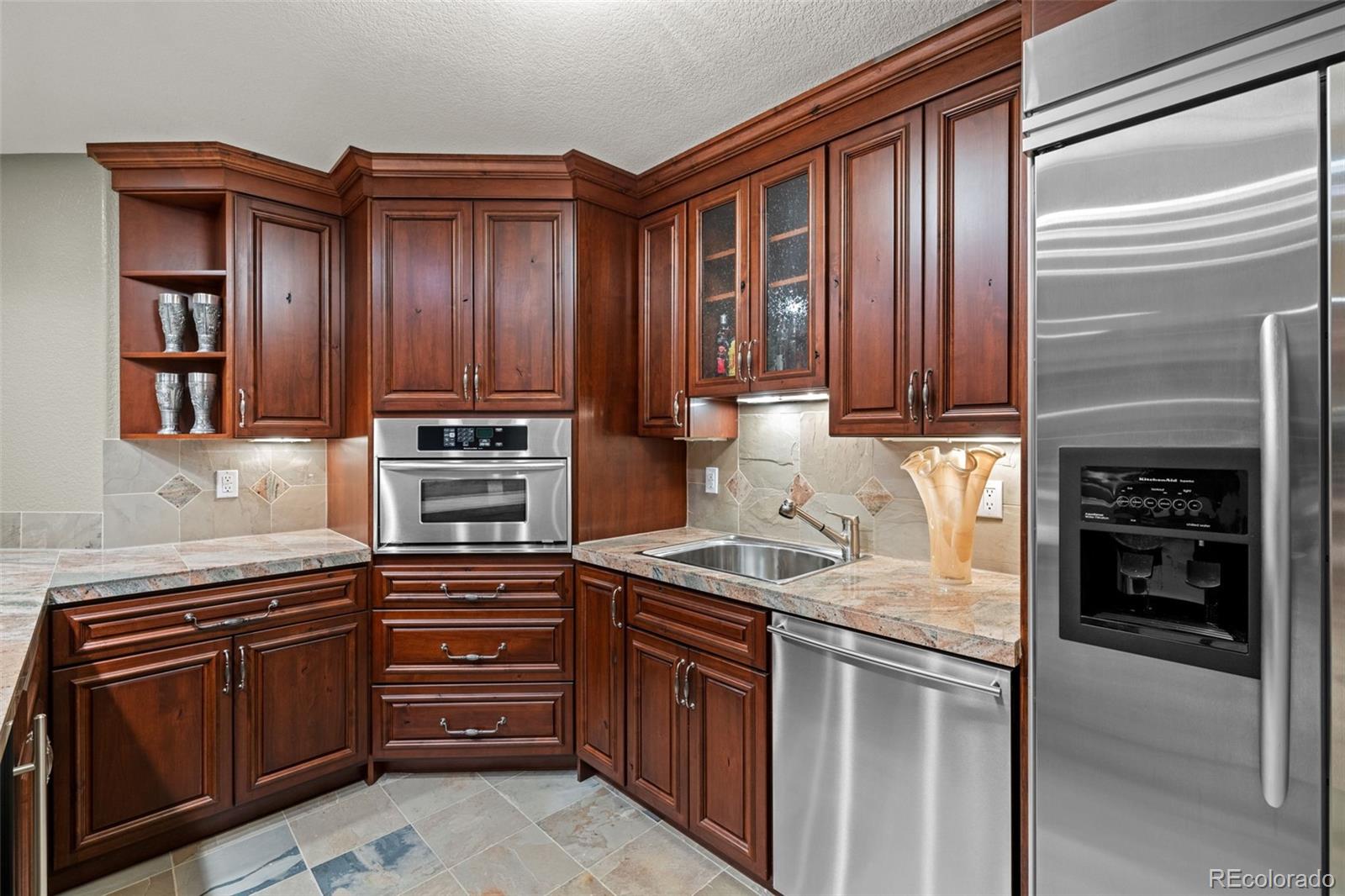 5 Redhawk Run Cherry Hills Village, CO 80113 - Photo 27 of 35 a kitchen with kitchen island granite countertop wooden cabinets stainless steel appliances and a sink