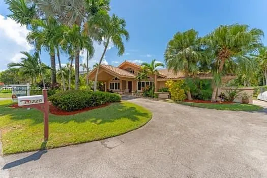 a view of a house with a yard and palm trees