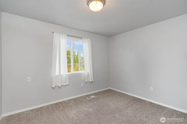 a view of an empty room with window and closet area