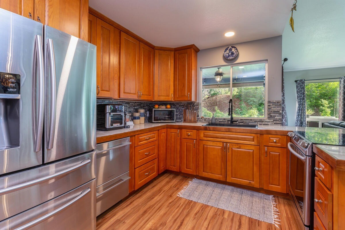 4845 Ohu Road Kapaa, HI 96746 - Photo 3 of 13 a kitchen with stainless steel appliances granite countertop a refrigerator a sink dishwasher a stove and white countertops with wooden floor