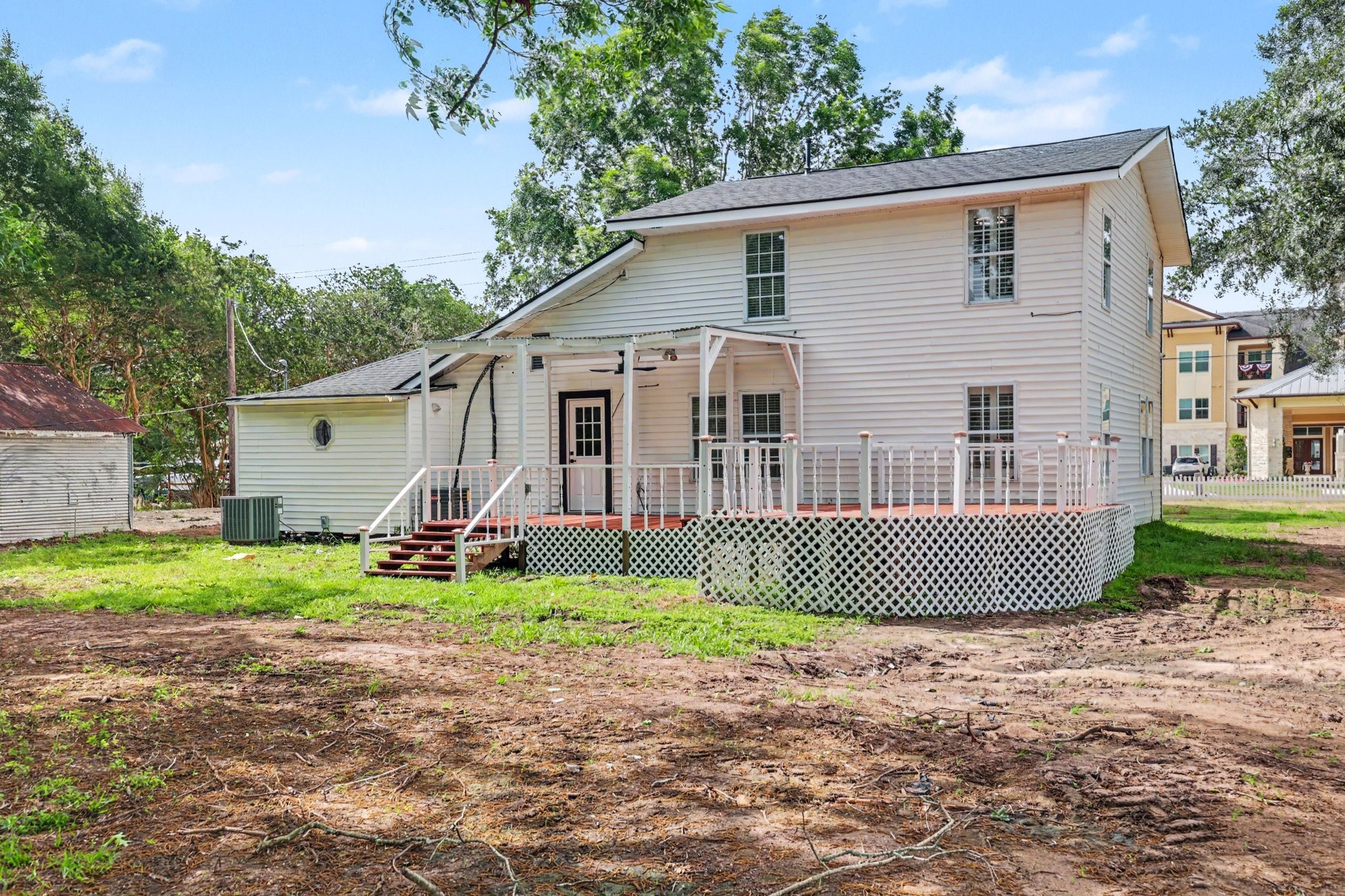 31730 Waller Tomball Road Waller, TX 77484 - Photo 45 of 50 This charming home features a spacious wooden deck with lattice detailing, perfect for outdoor gatherings. The large yard offers ample space for landscaping or recreational activities, surrounded by mature trees for added privacy.