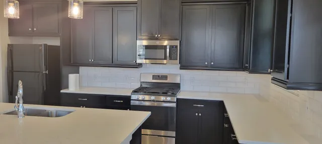 a kitchen with granite countertop a refrigerator and a stove top oven