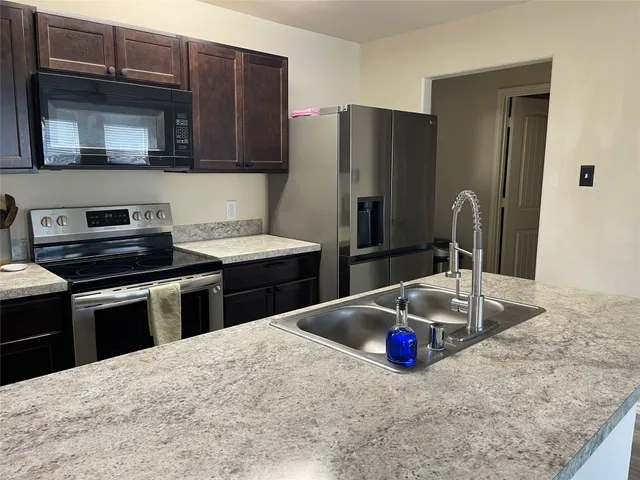 a kitchen with stainless steel appliances wooden cabinets sink and microwave