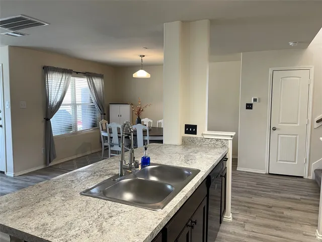 a kitchen with kitchen island granite countertop a sink a counter top space and cabinets